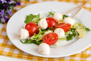 Appetizer on stick with tomato and mozzarella cheese.