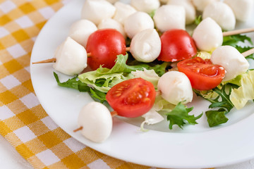 Appetizer on stick with tomato and mozzarella cheese.