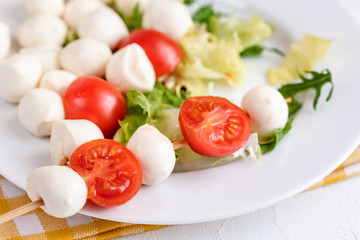 Appetizer on stick with tomato and mozzarella cheese.