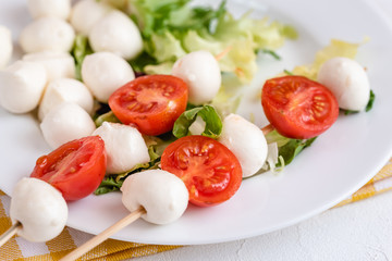 Appetizer on stick with tomato and mozzarella cheese.