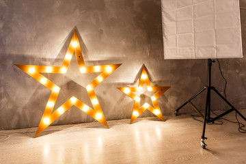 Large wooden star with a large number of lights are lit. Beautiful decor, design. Loft style Studio. Dark concrete background. Christmas, holiday, honorary star. Five stars 5 stars