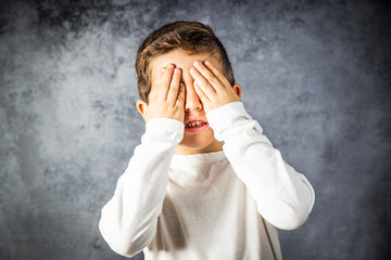 Portrait of a little boy covering his eyes