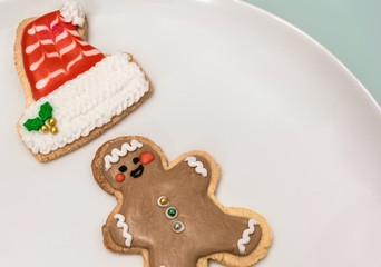 Traditional christmas cookies with shapes of a funny man and a santa hat on a white dish. Homemade biscuits with christmas decoration and copy space.
