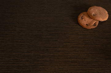 Two american homemade chocolate cookies on wooden table. Homemade irregular biscuits with copy space.