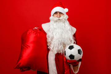Santa holds a classic football against red background
