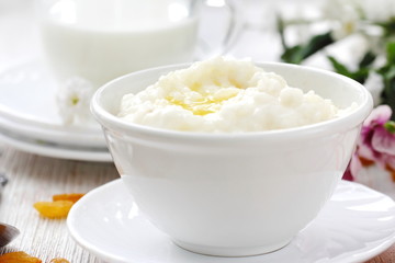 Sweet rice porridge with butter and mug of milk - obrazy, fototapety, plakaty