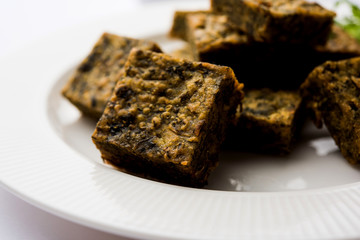 A savory cilantro cake or kothimbir vadi in square shape which is first steamed and then fried until crisp. popular indian snack served with hot tea and tomato ketchup