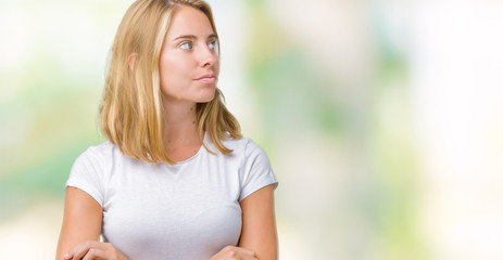 Beautiful young woman wearing casual white t-shirt over isolated background smiling looking to the side with arms crossed convinced and confident