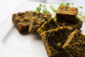 A savory cilantro cake or kothimbir vadi in square shape which is first steamed and then fried until crisp. popular indian snack served with hot tea and tomato ketchup