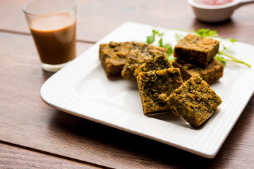 A savory cilantro cake or kothimbir vadi in square shape which is first steamed and then fried until crisp. popular indian snack served with hot tea and tomato ketchup