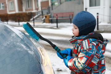 Kid scraping snow from car