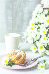 Delicious cake with coconut chips on pink plate on white table, autumn white chrysanthemum and cup of coffee