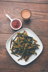 A savory cilantro cake or kothimbir vadi in square shape which is first steamed and then fried until crisp. popular indian snack served with hot tea and tomato ketchup