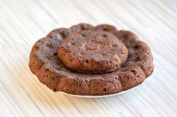 Chocolate almond pumpkin cake on white plate on colorful kitchen towel, tasty sweet dark brown biscuit