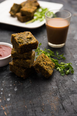 A savory cilantro cake or kothimbir vadi in square shape which is first steamed and then fried until crisp. popular indian snack served with hot tea and tomato ketchup
