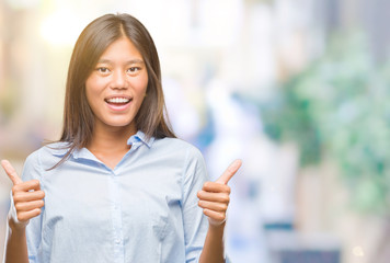 Fototapeta premium Young asian business woman over isolated background success sign doing positive gesture with hand, thumbs up smiling and happy. Looking at the camera with cheerful expression, winner gesture.
