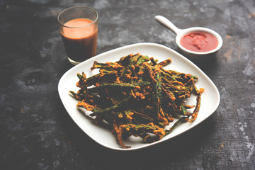 Kurkuri bhindi or crispy ladyfinger or okra fry recipe, served in a bowl with ketchup and hot tea. selective focus