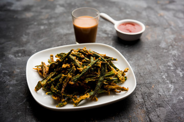 Kurkuri bhindi or crispy ladyfinger or okra fry recipe, served in a bowl with ketchup and hot tea. selective focus