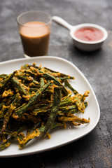 Kurkuri bhindi or crispy ladyfinger or okra fry recipe, served in a bowl with ketchup and hot tea. selective focus