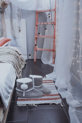 Stylish bedroom in gray tones, warm boots on the Mat near the bed of pallets.