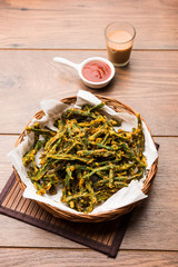 Kurkuri bhindi or crispy ladyfinger or okra fry recipe, served in a bowl with ketchup and hot tea. selective focus