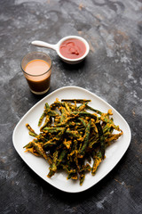 Kurkuri bhindi or crispy ladyfinger or okra fry recipe, served in a bowl with ketchup and hot tea. selective focus