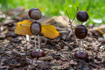 Angel and devil figures made from chestnuts and safety matches and dry leaves in the garden