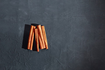 Dry cinnamon in the form of tubes on a black concrete background