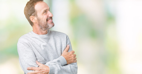 Naklejka na ściany i meble Handsome middle age senior man wearing a sweatshirt over isolated background smiling looking to the side with arms crossed convinced and confident