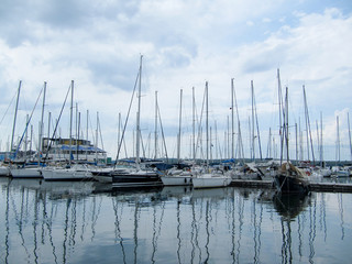 Fototapeta na wymiar sailing yachts stand with sails lowered in a small port on a cloudy day.