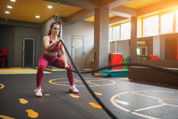 Sportive woman training with battle ropes