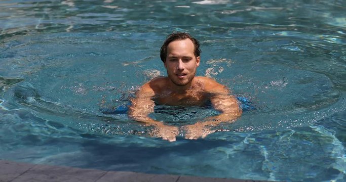 Man swimming in swimming pool in resort hotel on vacation.