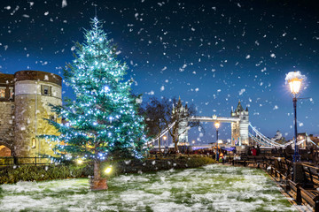 Winter in London Konzept: Weihnachtsbaum vor der Tower Bridge mit Schneefall bei Nacht