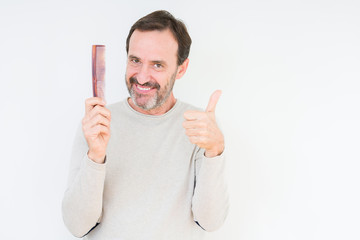 Senior man holding hair comb over isolated background happy with big smile doing ok sign, thumb up with fingers, excellent sign