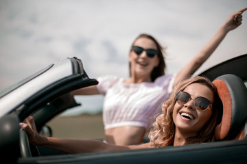 Obraz na płótnie Canvas close up.two happy young women in a convertible car