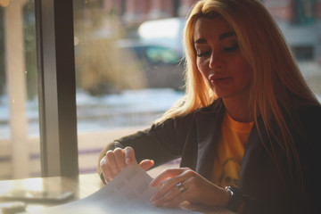 A girl sitting in a cafe leafing through the menu is a romantic image.