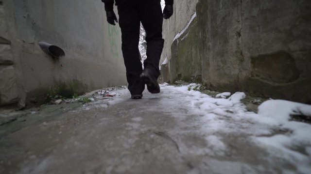 Man with backpack walks down a narrow alley in winter