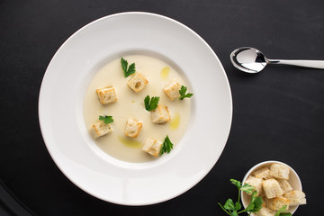 cream soup with parsley and bread on black bakground