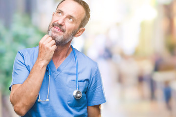 Fototapeta premium Middle age hoary senior doctor man wearing medical uniform over isolated background with hand on chin thinking about question, pensive expression. Smiling with thoughtful face. Doubt concept.