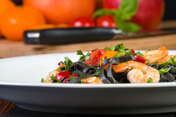 Black squid ink Fettuccine pasta with prawns or shrimps cherry tomatoes, parsley, chili in wine and butter sauce.