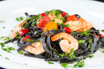 Black squid ink Fettuccine pasta with prawns or shrimps cherry tomatoes, parsley, chili in wine and butter sauce.