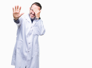 Middle age senior hoary professional man wearing white coat over isolated background covering eyes with hands and doing stop gesture with sad and fear expression. Embarrassed and negative concept.