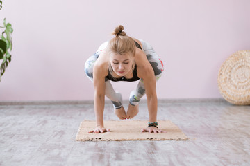Yoga woman training on exercise mat and doing balance yoga poses on white background. Astavakrasana or symmetrical arm balance pose.