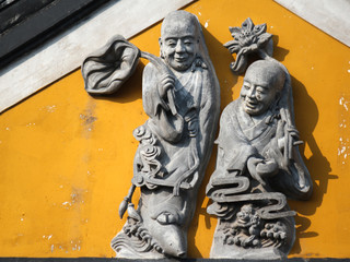 Stone carving showing two monks with a lotus flower as symbolic religious plant on a temple in a Chinese old town, China, Asia