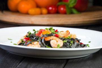 Black squid ink Fettuccine pasta with prawns or shrimps cherry tomatoes, parsley, chili in wine and butter sauce.