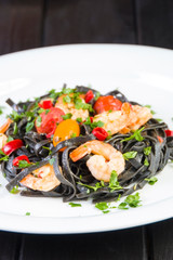 Black squid ink Fettuccine pasta with prawns or shrimps cherry tomatoes, parsley, chili in wine and butter sauce.