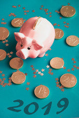 Chinese symbol of the new year 2019 golden pig on the background of chocolate coins and stars.Piggy bank for luck.Low angel view.