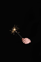Man's hand holding burning sparkler on a black background