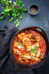 Traditional French Corsican fish stew with prawns, mussels and fish as top view in a modern design Japanese cast-iron roasting dish