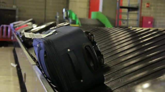 Static shallow focus on luggage bags travelling on conveyor belt in airport.